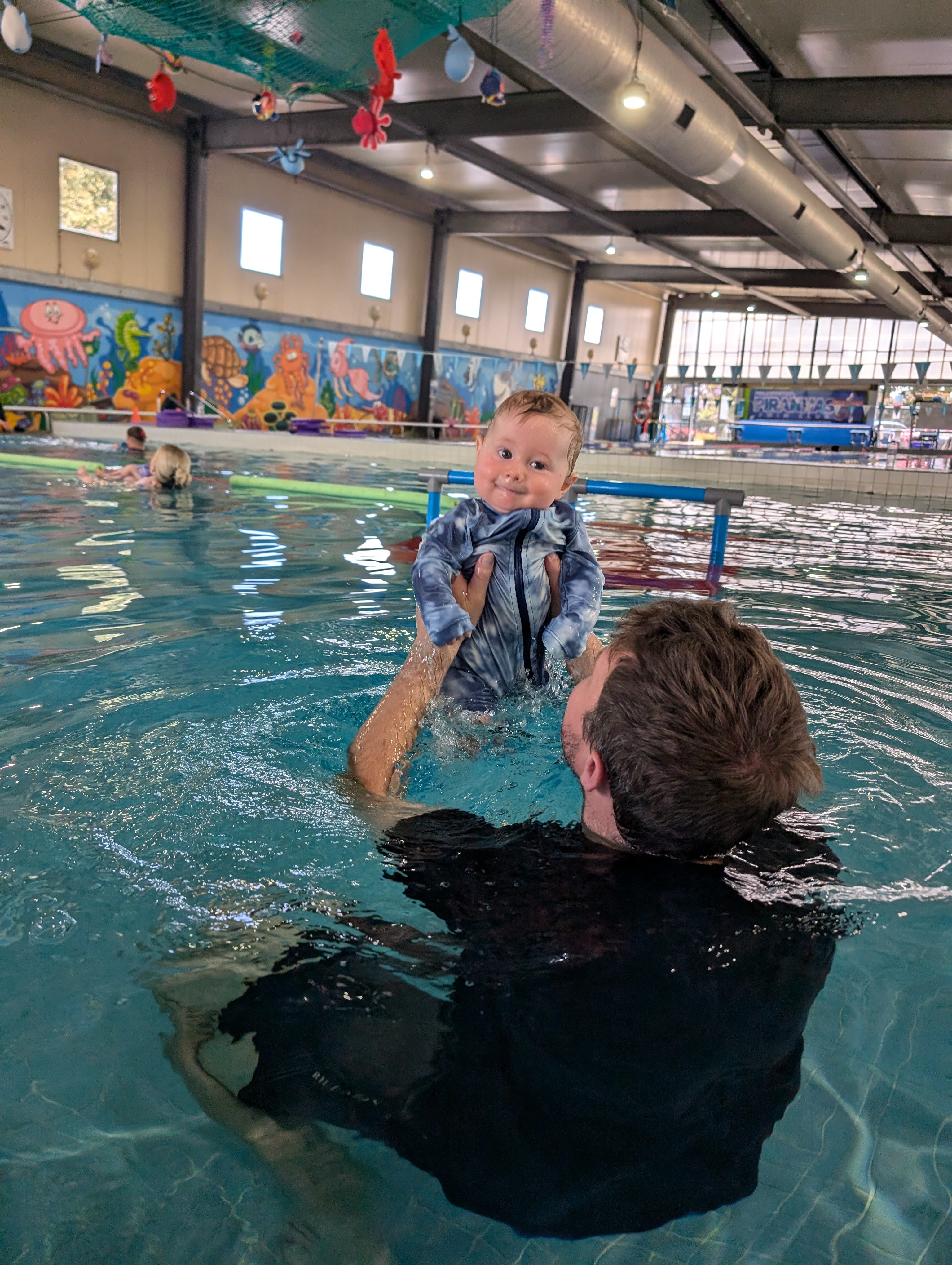 Dad holding and engaging with baby during AquaBabies lesson at Holsworthy Aquatic Centre.